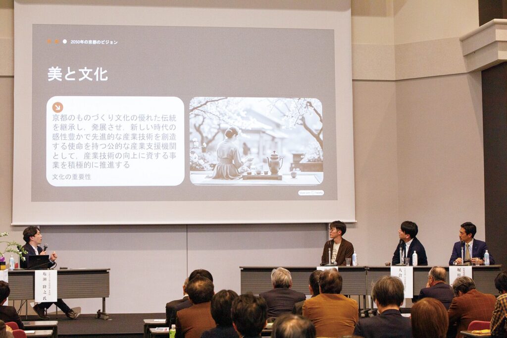 ステージ上のスクリーンに「美と文化」というタイトルと2050年の京都のビジョンに関するスライドが投影され、登壇者たちが聴衆を前にディスカッションを行っている様子