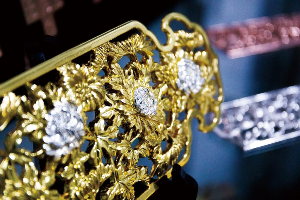 菊の花をモチーフにした精巧な透かし彫りが施された、金色のアクセサリーのクローズアップ