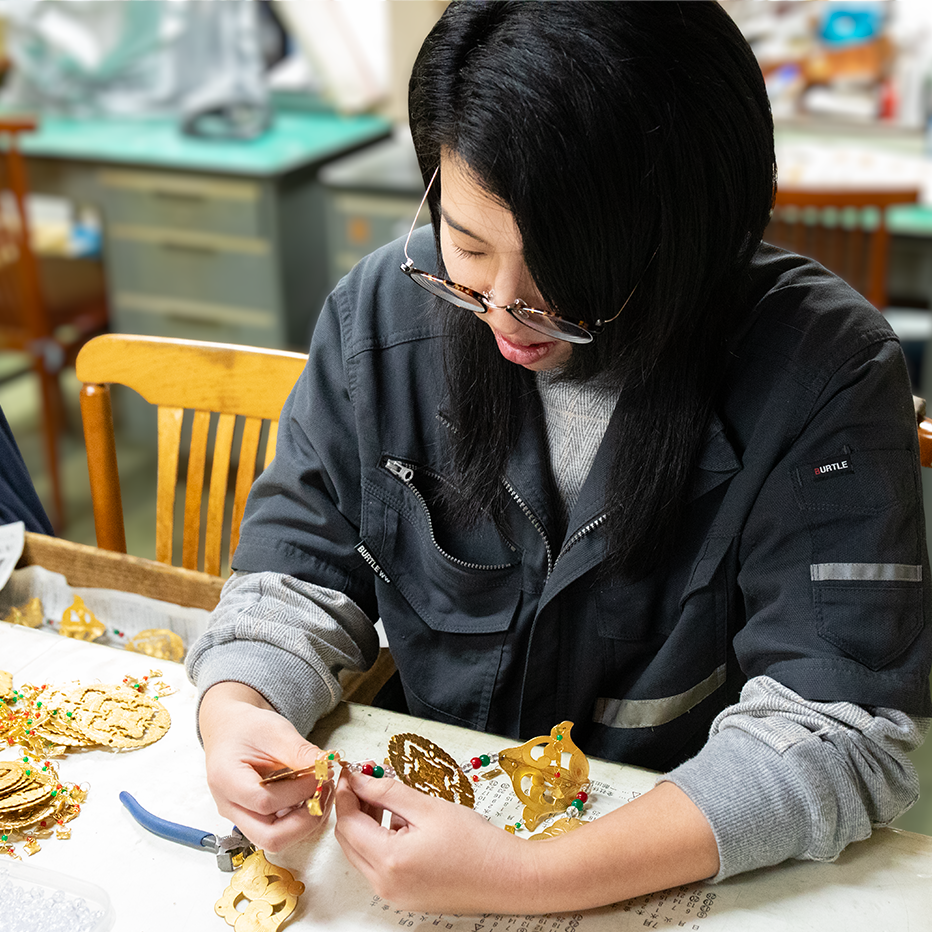 金色の細かな装飾パーツを組み合わせて伝統工芸品の制作を行う山田 智世氏