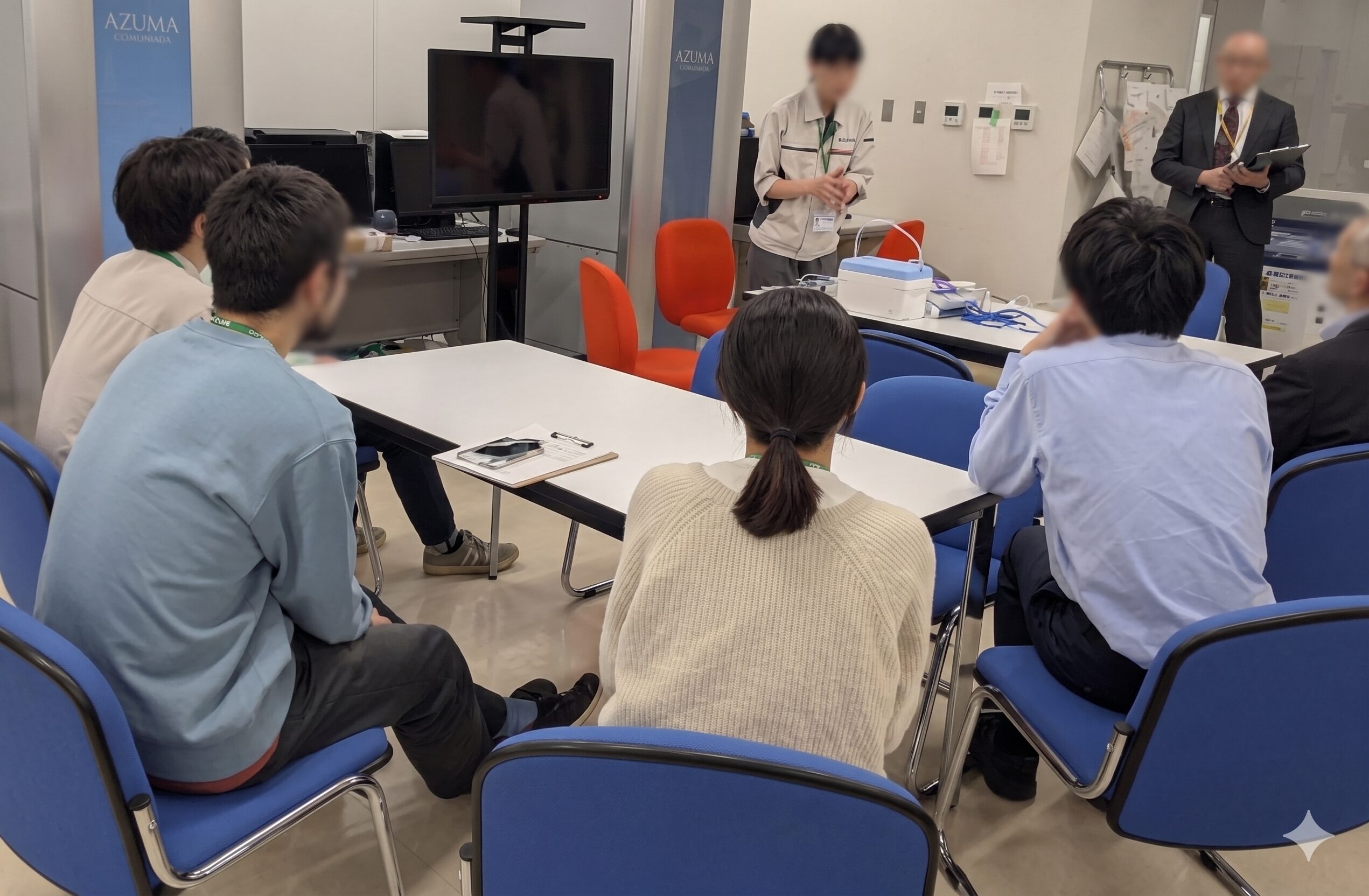 スタッフが机上の機器を使いながら、参加者に説明を行っている様子